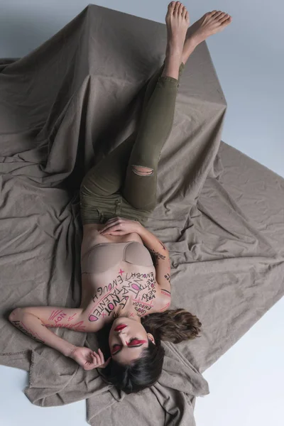 Jovem morena bonito modelo fino em jeans skinny deitado no chão — Fotografia de Stock