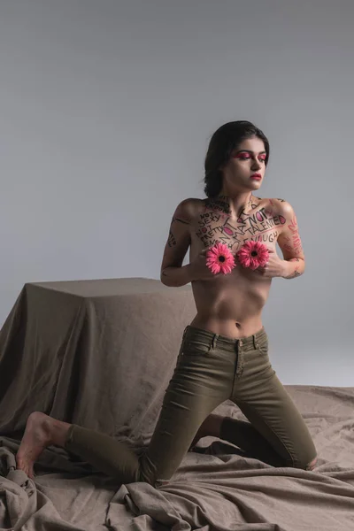 Junge Brünette hübsches halbnacktes Modell in engen Jeans, das Stigmata demonstriert — Stockfoto