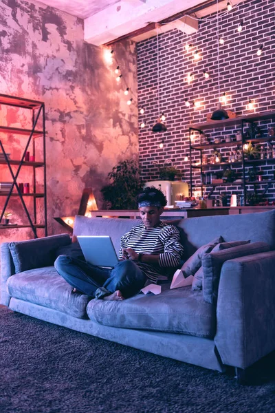 Jonge man in afwachting van de komst van vrienden zitten met een laptop op schoot en het maken van papier vliegtuigen. — Stockfoto