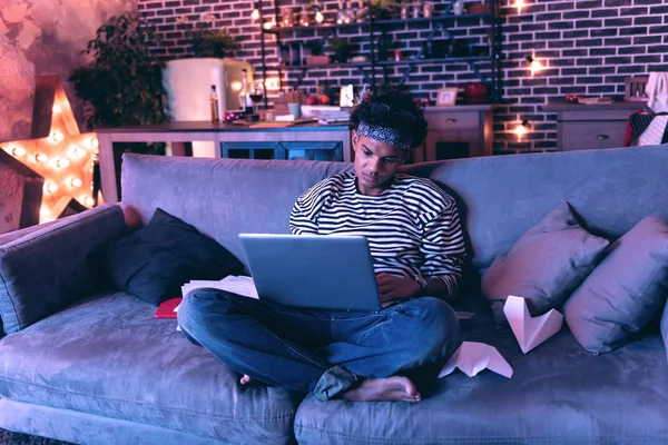 Молодий чоловік намагається працювати на робочому ноутбуці у святковий вечір . — стокове фото