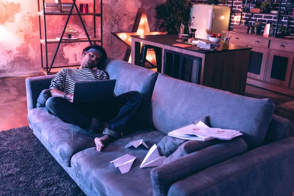 Estudiante masculino que se queda dormido debido a la música durante la preparación para el examen justo en el sofá . — Foto de Stock