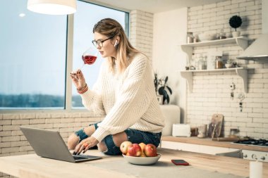 Örme kazak kırmızı şarap taşıyan uzun saçlı kadın