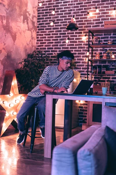 Хлопчик сидить біля лампи у формі зірки і грає в гру на ноутбуці . — стокове фото