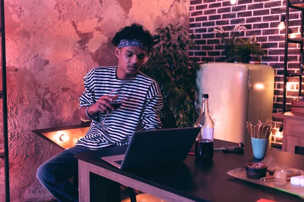 Relaxed African American boy trying to pass online training while drinking wine. — Stock Photo, Image