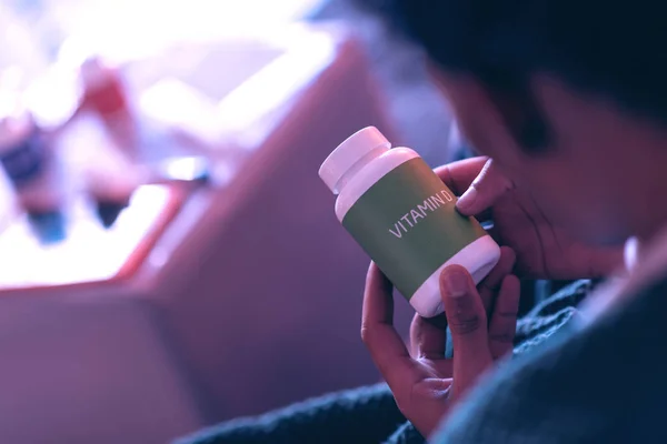 Κοντινό πλάνο ενός νεαρού άνδρα που κατέχουν ένα πράσινο βάζο στα χέρια του, που λέει ότι αυτό είναι η βιταμίνη D. — Φωτογραφία Αρχείου