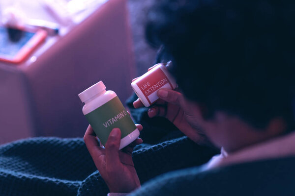 Крупный план афроамериканского пациента, изучающего бутылки с лекарствами, чтобы выбрать правильный
.