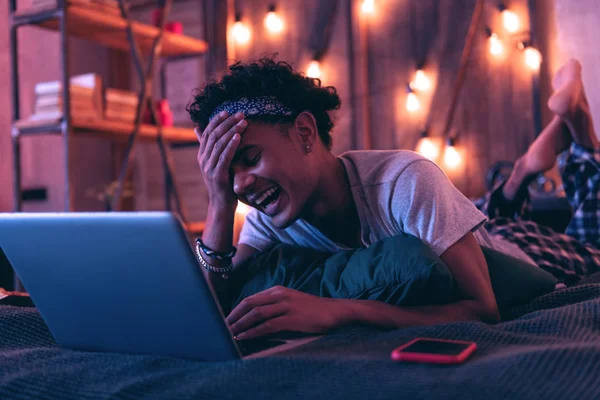 Улыбающийся афроамериканец счастлив общаться со своими друзьями, расслабляясь в постели . — стоковое фото