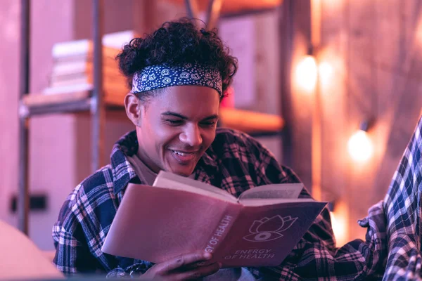 Junge lächelt überraschend offen zu romantischer Geschichte, die er in seinem Buch liest. — Stockfoto