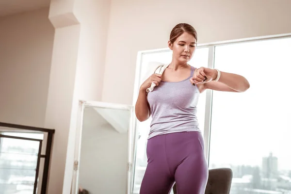 Mujer cansada decidida comprobando el tiempo en su reloj blanco — Foto de Stock