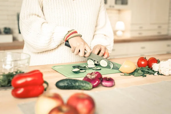 Nauwkeurige geschoolde vrouw snijden komkommer met professionele mes — Stockfoto