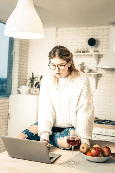 Long-haired Dziewczyna w stylowe dżinsy chropowaty, działa na jej laptopie — Zdjęcie stockowe