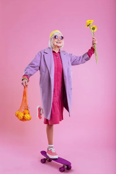 Пожилая леди, стоящая на коньках с подсолнухами и фруктами — стоковое фото