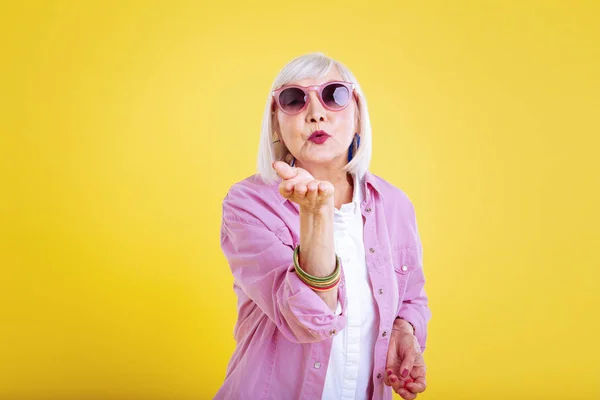 Frumoasă doamnă în vârstă purtând jachetă roz strălucitoare trimitând sărut de aer — Fotografie, imagine de stoc