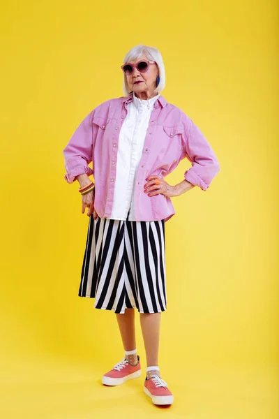 Modern elderly lady posing while taking part in photo session