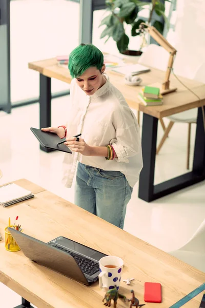 Pleasant green haired woman holding a graphic tab