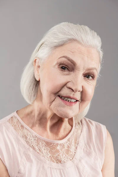 Beaming old woman with short hair working as model in studio