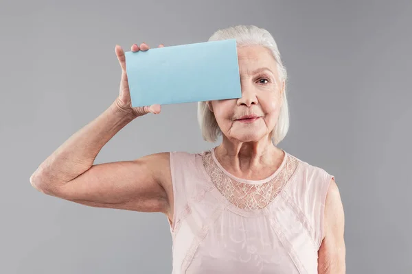 Neutraal grijs-haired oude vrouw naakt kleding dragen en verbonden blauwe naamplaatje — Stockfoto