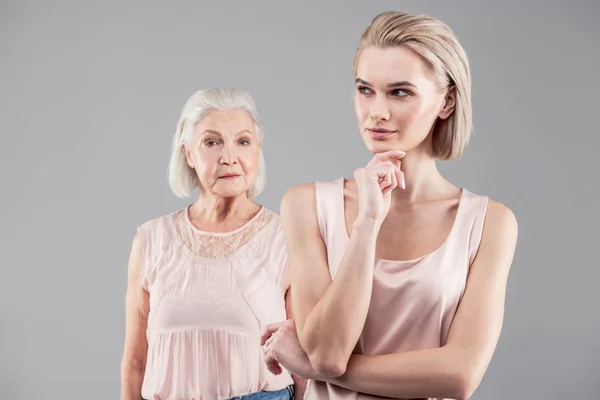 Pensive blonde girl looking evil while touching her chin — Stock Photo, Image