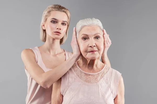Neutrale knappe jonge dame strak sluiten oren van oude moeder — Stockfoto