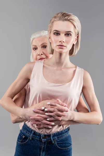 Menina loira séria cruzando mãos e dedos com sua mãe sênior — Fotografia de Stock