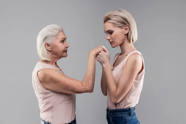 Благодарная блондинка с короткой стрижкой дышит на руках старшей матери — стоковое фото