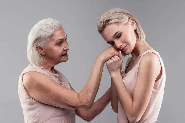 Sorrindo pacífica jovem mulher colocando a cabeça nas mãos de sua mãe — Fotografia de Stock