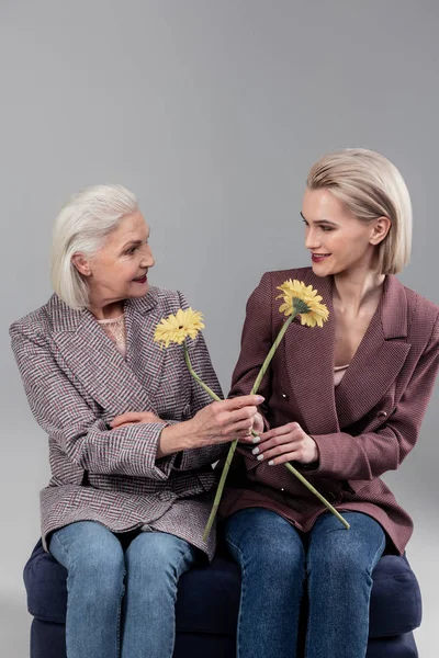 Gråhåriga äldre dam föreslår hennes dotter blomma — Stockfoto