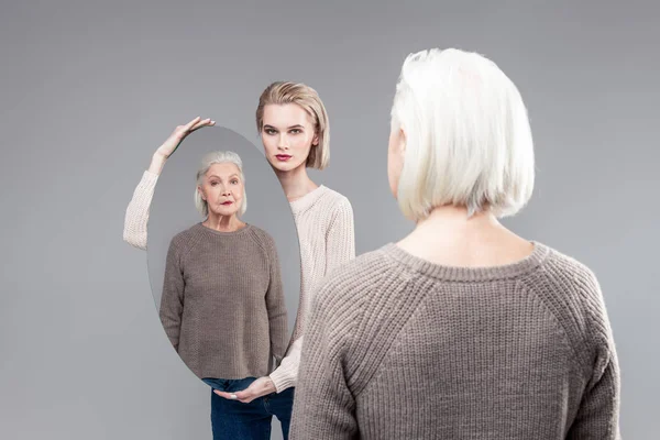 Serios blonda fata arată mama ei cu ajutorul oglinzii ovale — Fotografie, imagine de stoc