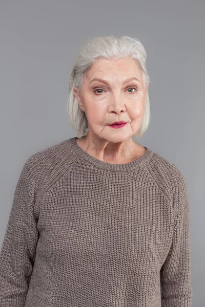 Stara kobieta z fryzura bob, posiadanie, ciemne szminka podczas noszenia sweter szary — Zdjęcie stockowe