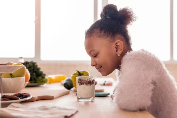Krullend Afro-Amerikaanse meisje op zoek naar zoete pudding met noten — Stockfoto
