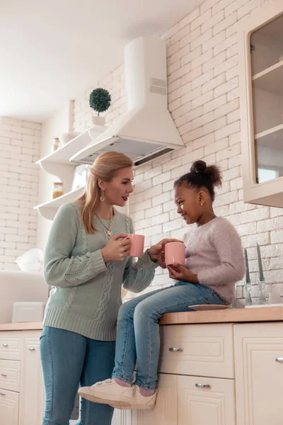 Blonde-haired mother drinking tea with daughter before work — Stock Photo, Image