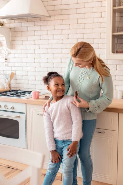 Caring mother sharing chocolate cookie with daughter — Stock Photo, Image