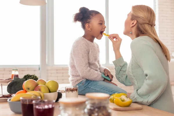 Loira de cabelos mãe alimentando sua menina engraçada bonito com frutas — Fotografia de Stock