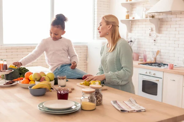 Söt lockiga dotter titta på mamman matlagning sallad — Stockfoto