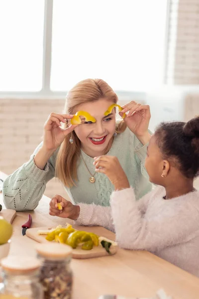 Äiti pitää hauskaa leikkaamalla pippuria kasvattilapsensa kanssa — kuvapankkivalokuva