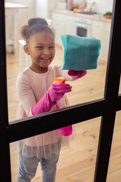 Маленькая веселая дочурка занята уборкой за дверью — стоковое фото
