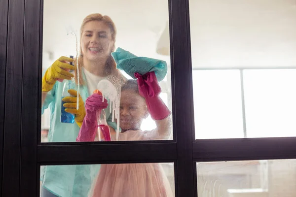 Blonde-haired mother feeling joyful having very helpful daughter — Stock Photo, Image