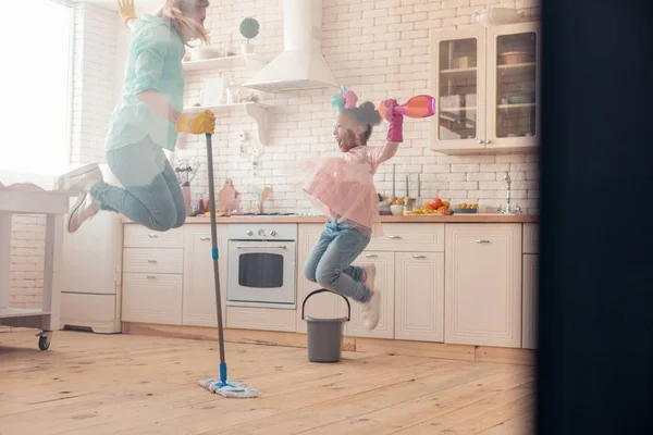 Mother and daughter jumping high after finishing the cleaning — Stock Photo, Image