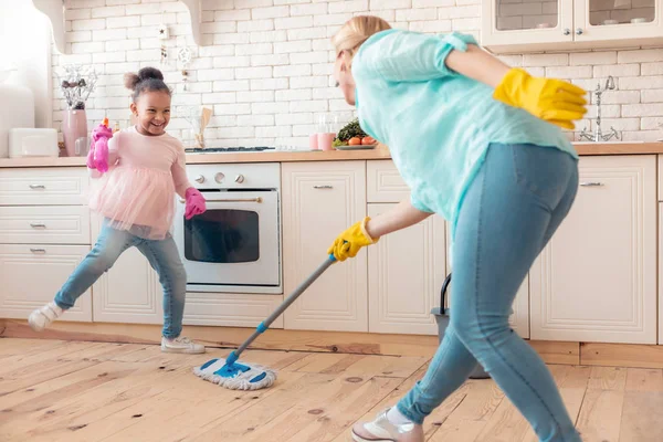 Mor och dotter bär handskar moppning golvet i köket — Stockfoto