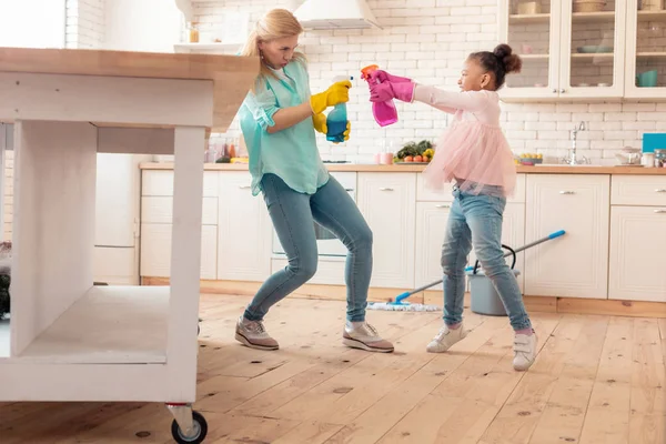 Madre e figlia si divertono con la pulizia spray in cucina — Foto Stock