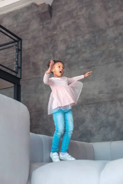 Fröhliches kleines Mädchen lacht, während es Spaß hat und springt — Stockfoto