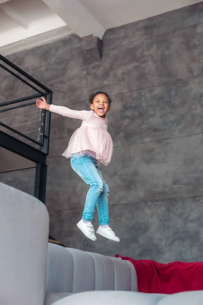 Riendo chica radiante bailando y saltando en el sofá — Foto de Stock