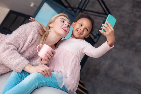 Madre mostrando su lengua mientras hace la foto con su hija —  Fotos de Stock