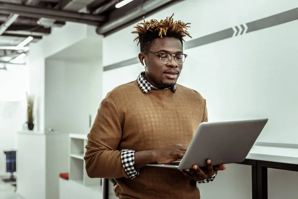 Αφρικανικός Αμερικανός προγραμματιστής σε καθαρά ποτήρια κρατώντας το laptop — Φωτογραφία Αρχείου
