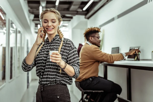 Gut aussehende, sympathische junge Frau mit Anruf bei der Arbeit — Stockfoto