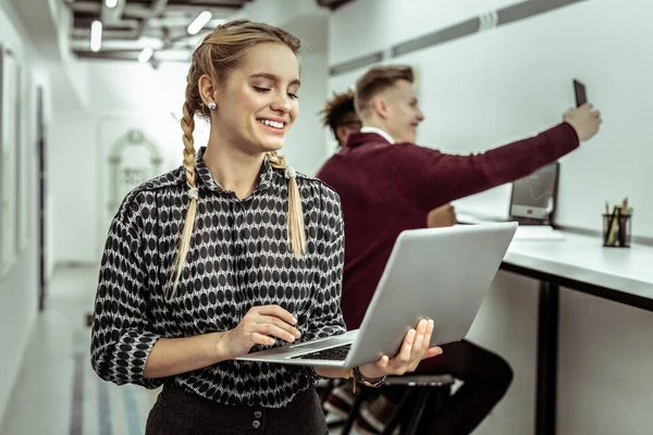 Sorrindo mulher loira com duas tranças segurando laptop fino — Fotografia de Stock