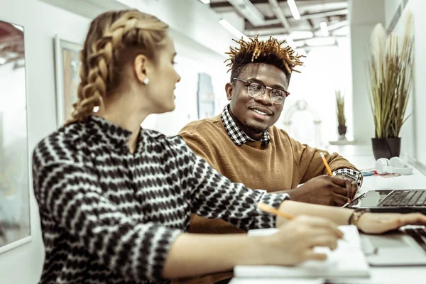 Afrikanisch-amerikanischer kurzhaariger Mann schaut angenehm auf weibliche Arbeitskollegin — Stockfoto