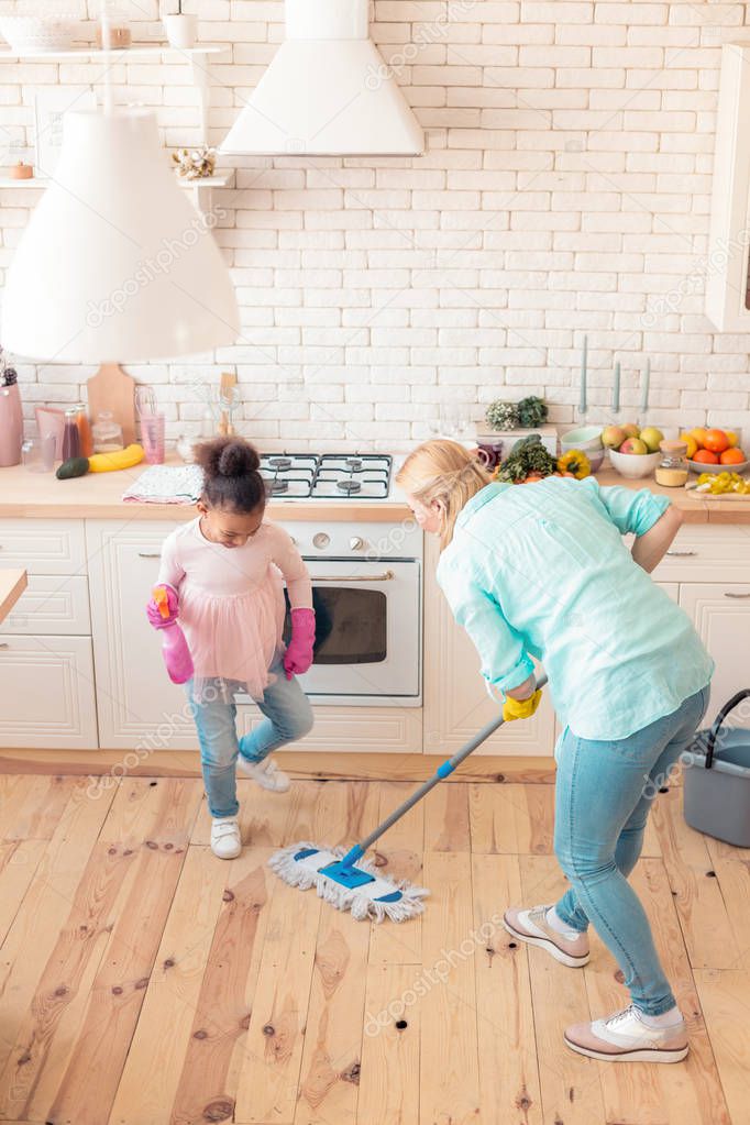 Girl wearing jeans and pink shirt helping mom with cleaning