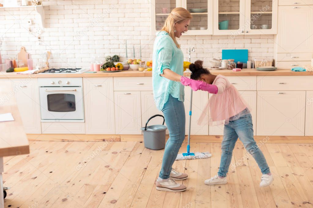 Mother and daughter wearing jeans and sneakers cleaning flat