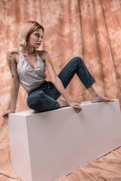 Agradable mujer atractiva sentada en el cubo blanco — Foto de Stock